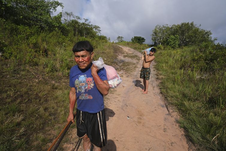 Surucucu (RR), 09/02/2023 - Pedro e Natanael, homens yanomami caminham com suprimentos em trilha no Surucucu, na Terra Indígena Yanomami. Foto: Fernando Frazão/Agência Brasil